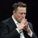 Shock Win: Musk’s Two Words Ignite Europe Elon Musk in a suit deep in thought, black background.