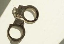 Toddler Waves Loaded Gun; Cop Arrested A pair of metallic handcuffs resting on a light surface