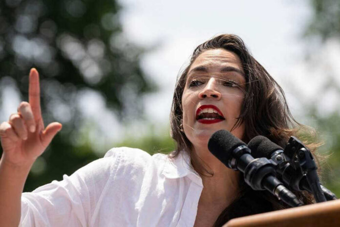 shutterstock_2480447435 Alexandria Ocasio-Cortez speaking at an outdoor event.