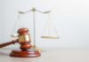 Murder Case CRACKED — Jury Drops Hammer A wooden gavel in front of a balance scale symbolizing justice