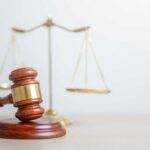 Murder Case CRACKED — Jury Drops Hammer A wooden gavel in front of a balance scale symbolizing justice