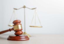 Murder Case CRACKED — Jury Drops Hammer A wooden gavel in front of a balance scale symbolizing justice