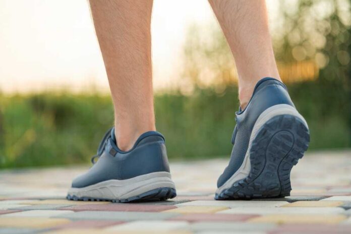 Walking,On,Colorful,Pavement,Wearing,Comfortable,Shoes,During,Sunset,In Two individuals walking on a path during sunset
