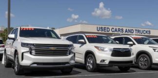 Two white SUVs parked at a used car dealership with price tags visible