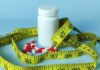 Old Pill TORCHES Fat — Muscle Spared? A white pill bottle surrounded by red and white capsules and a yellow measuring tape