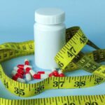 Old Pill TORCHES Fat — Muscle Spared? A white pill bottle surrounded by red and white capsules and a yellow measuring tape