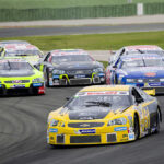 Race cars on Daytona track with large audience watching