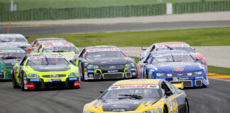 Race cars on Daytona track with large audience watching