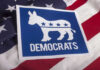 VIDEO: Armed Rush At Dem Candidate Stuns Crowd Democrats logo on American flag background.