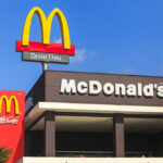McDonald's restaurant exterior with drive-thru signs against blue sky