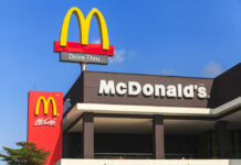 McDonald’s ‘Heist’ Menu Launched Today McDonald's restaurant exterior with drive-thru signs against blue sky