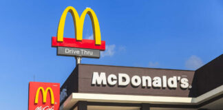 McDonald's restaurant exterior with drive-thru signs against blue sky