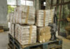 HUGE: Narco-Terror Boss Now in U.S. Stacked packages wrapped in plastic next to a rifle in a warehouse setting