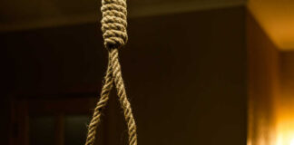 A close-up of a noose hanging in a dimly lit room