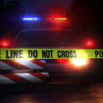 Grim Find Near Killer Rapid Police car with flashing lights behind caution tape.