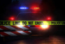 Grim Find Near Killer Rapid Police car with flashing lights behind caution tape.