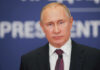Putin Caves to America Vladimir Putin at a podium in a dark suit and red tie