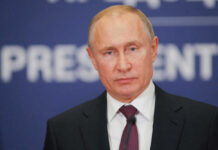 Putin Caves to America Vladimir Putin at a podium in a dark suit and red tie