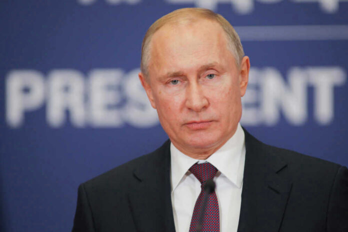 shutterstock_1287905686 Vladimir Putin at a podium in a dark suit and red tie