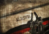 Close-up of metal handcuffs on a grungy surface with the word MURDER