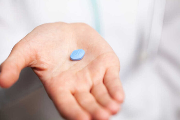Doctor,Close,Up,Holding,Pills,For,Men's,Sexual,Health Cancer cells spreading on a blue surface.