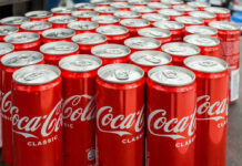 Coca-Cola’s Flavor Bomb Lands 2027 Coca-Cola cans stacked on a surface.