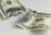 Torn and crumpled hundred dollar bills on a white surface
