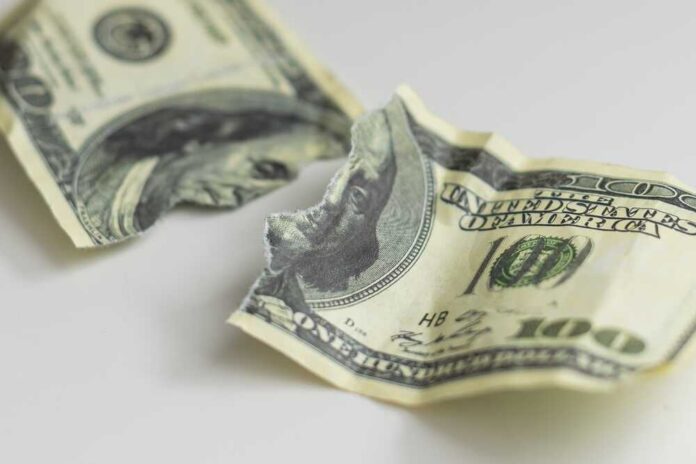 A,One,Hundred,Dollar,Bill,Torn,In,Half,Isolated,On Torn and crumpled hundred dollar bills on a white surface