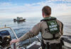 Smuggling Boat Snagged Off America’s Coast Border Patrol officer on boat watching another boat.