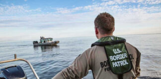 Border Patrol officer on boat watching another boat.