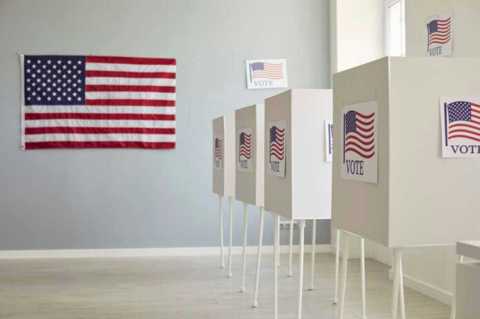 shutterstock_2475726979 Polling booths with American flags and Vote signs.