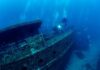 Divers exploring a sunken shipwreck underwater
