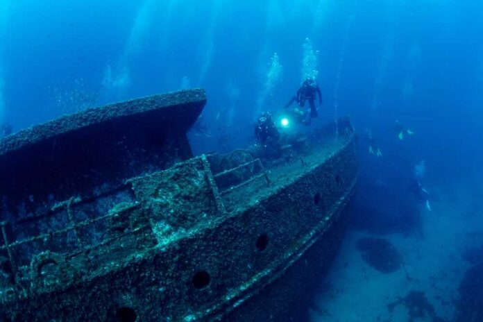 Divers,Group,Diving,Near,Of,The,Wreck,Of,Old,Ship Divers exploring a sunken shipwreck underwater