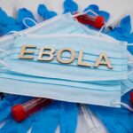 Ebola Lands – Then Tragedy Face masks with lab vials and gloves arranged around them