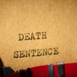 Chaotic Execution – Mic Cuts, Snoring Continues Typewriter typing the words death sentence on paper