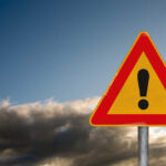 Deliberate Attack Hits Lawmaker A triangular warning sign with an exclamation mark against a cloudy sky